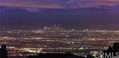 Panoramic view of a cityscape at night, showcasing a wide expanse of city lights under a twilight sky.