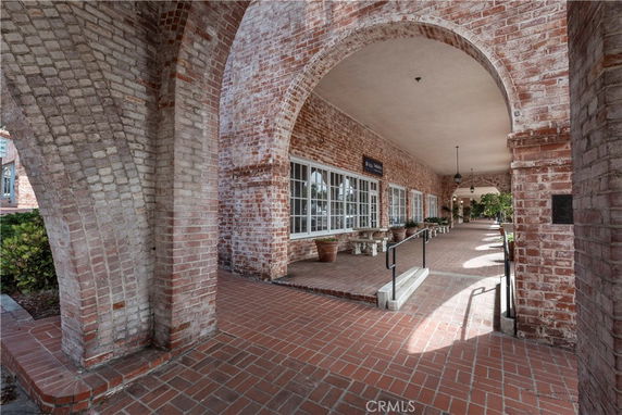 Exterior view of a brick building with arches and a walkway.