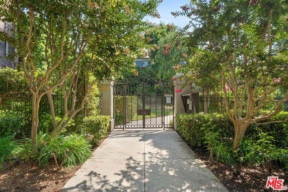 Front view of a gated entrance to a residential property with surrounding greenery.