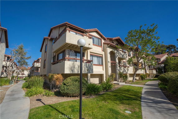 Front view of a multi-story residential building with balconies and a pathway leading to the entrance.