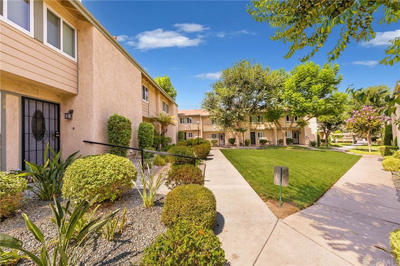 Pathway and landscaped area between two residential buildings with trees and bushes.