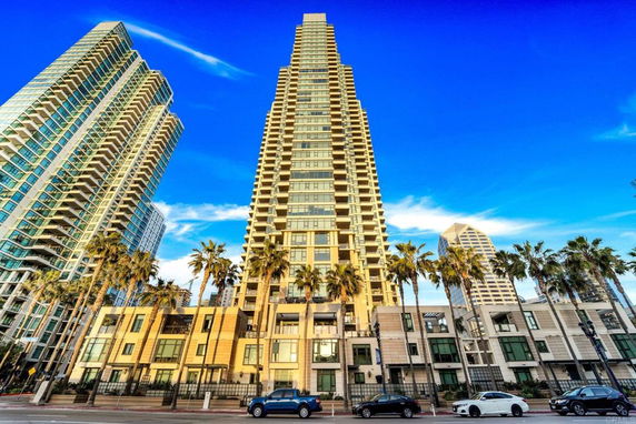 Front view of a high-rise building complex with multiple towers and palm trees in the foreground.