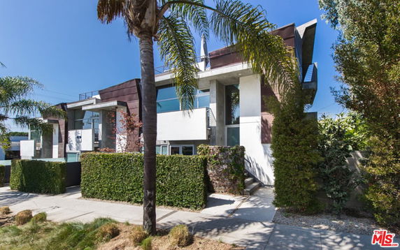 Front view of a modern multi-story house with large windows and contemporary design.