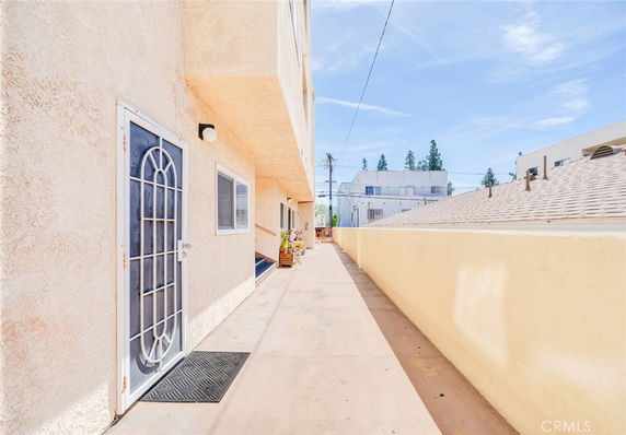 Exterior walkway of a building with a view of adjacent rooftops and distant buildings.