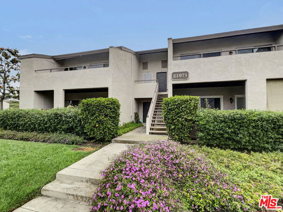 Front view of a two-story residential building with balconies and a central staircase.