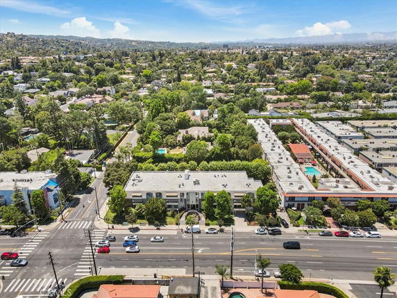 Wide-angle aerial view of a suburban area with roads, buildings, and greenery.