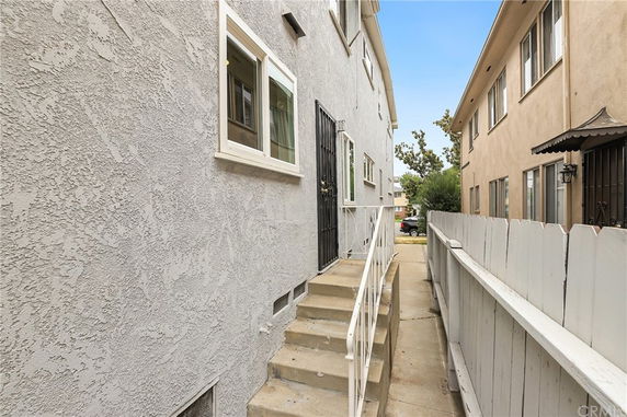 Side view of a multi-story building with white stucco walls and windows.