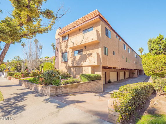 Front view of a multi-story building with balconies and a tile roof.