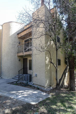 Front view of a two-story house with a balcony and front steps.