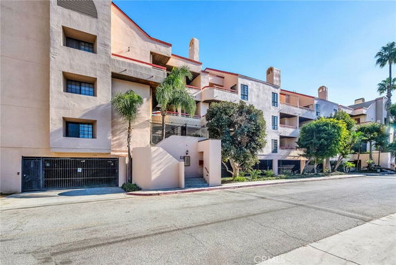 Front view of a multi-story apartment building with balconies and entryway.