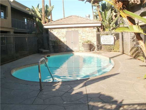 Outdoor swimming pool with surrounding fencing and a small building nearby.