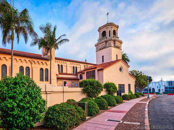 Front view of a church building with a tower and cross on top.