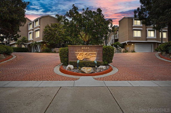 Front view of multi-story buildings with garages and a central driveway entrance.