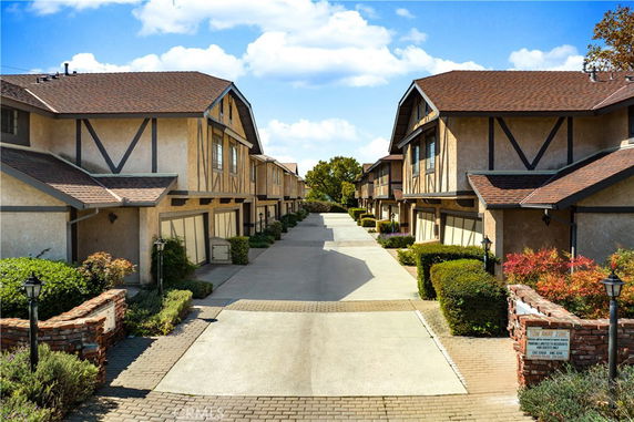 Front view of a row of attached two-story houses with garages and pitched roofs.