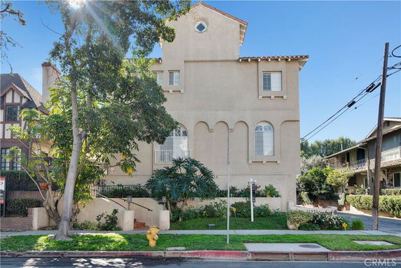 Front view of a multi-story building with arched windows and a sloped roof.