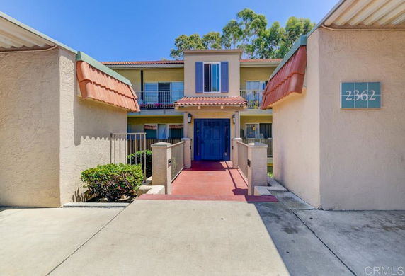 Front view of a two-story house with a blue door and red-tiled roof.