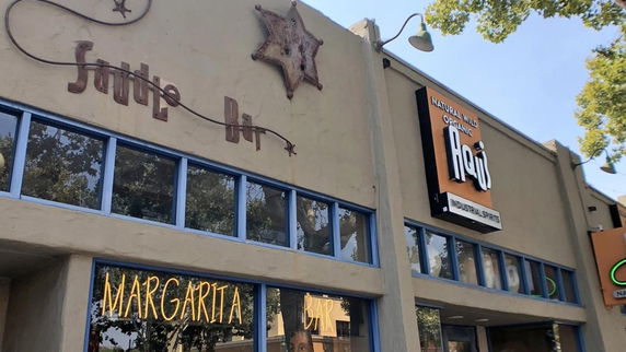Front view of a building with signs for a bar and organic spirits store.