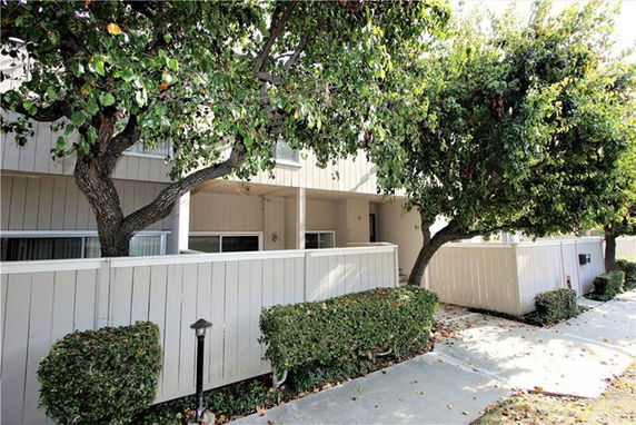 Front view of a two-story house with a fenced yard and trees.