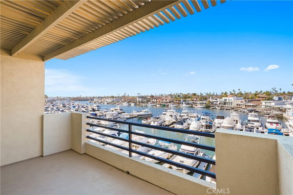Balcony view overlooking a marina filled with numerous boats and a waterway with houses in the background.