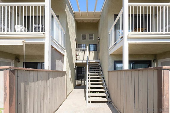 Exterior view of a two-story apartment building with balconies and central staircase.