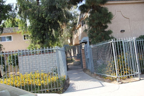Front view of a house with a gated entrance and surrounding greenery.