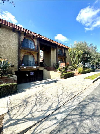 Front view of a multi-story building with balconies and a tiled roof.
