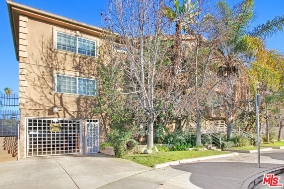 Front view of a multi-story building with large windows and gated entrance.