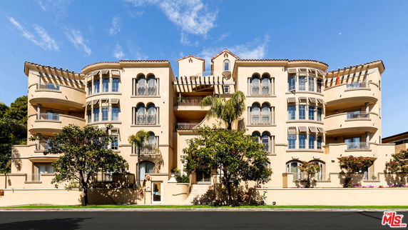 Front view of a multi-story apartment building with balconies and decorative architectural features.