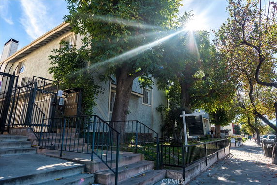 Front view of a multi-story house with a staircase and gated entrance.