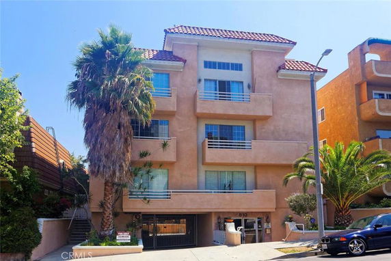 Front view of a multi-story residential building with balconies and a gated entrance.