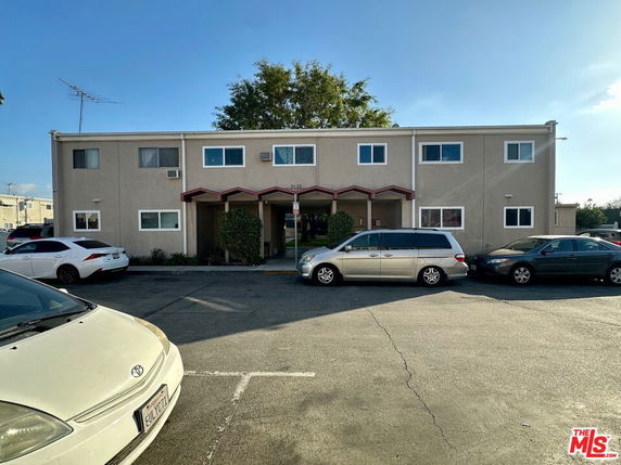 Front view of a two-story apartment building with parking area in front.