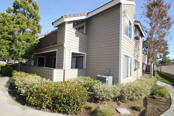 Front view of a two-story house with beige siding and a small porch.