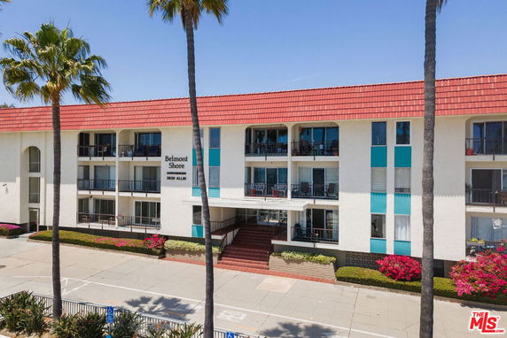 Front view of a multi-story residential building with balconies and a tiled roof.