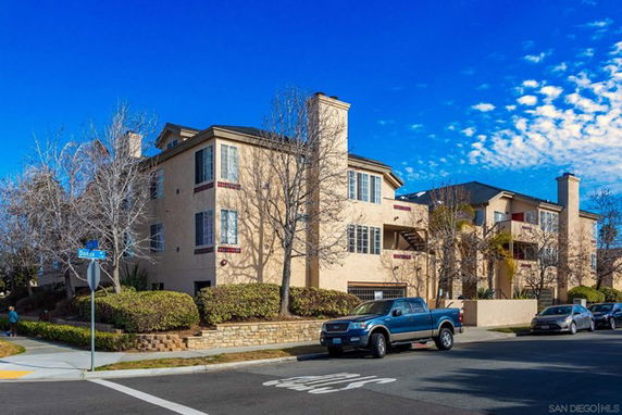 Street view of a multi-story residential building with beige exterior and multiple chimneys.