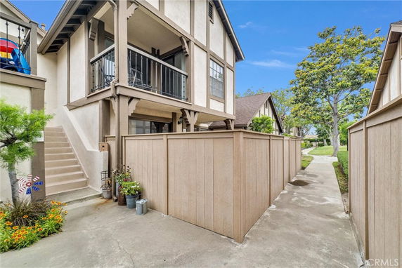 View of a two-story house with a wooden fence and exterior stairs.