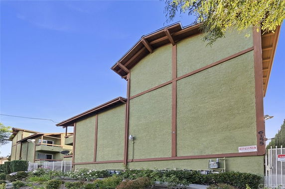 Side view of a multi-story building with sloped roofs and green exterior walls.