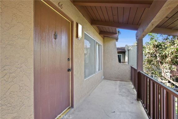 Front view of a residential building entrance with a brown door and window.