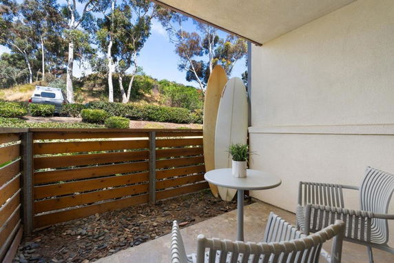 Outdoor seating area with a view of trees and parked car.