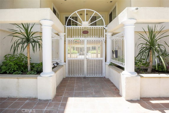 Front view of a gated entrance to a building with white columns and decorative plants.