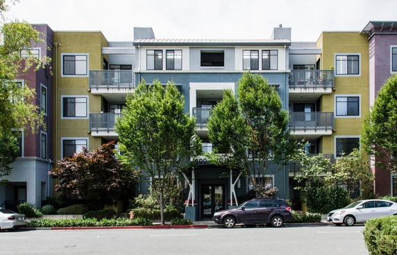 Front view of a multi-story apartment building with balconies and various colored sections.