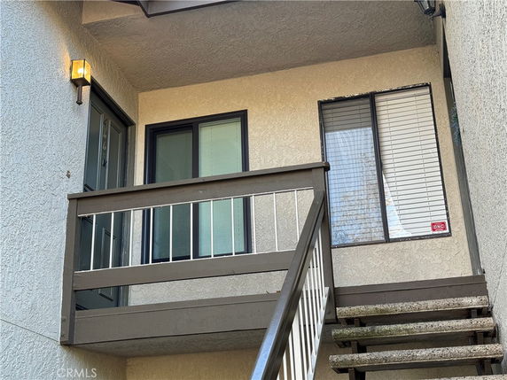 Exterior entrance of a building with a staircase leading to a door and window.