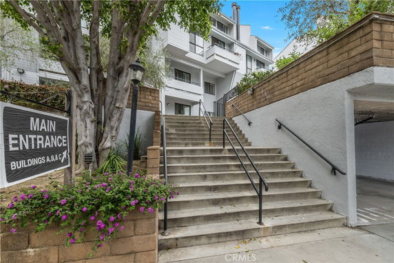 Front view of a multi-story apartment building with stairs leading to the main entrance.