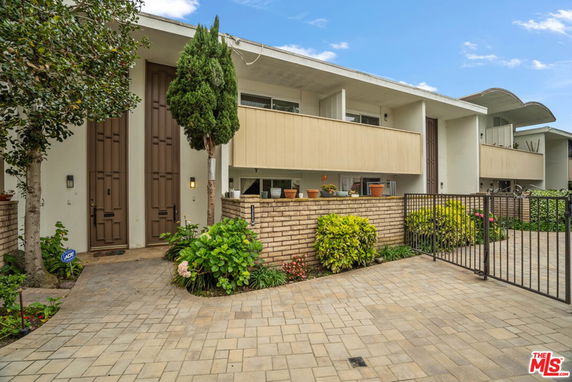 Front view of a modern two-story house with balconies and a gated entrance.