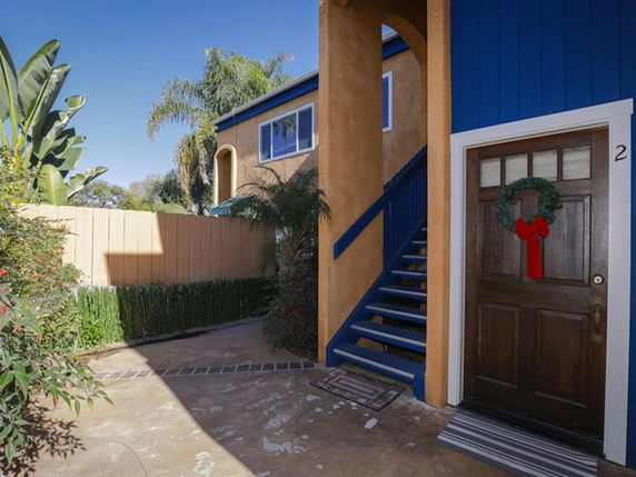 Front view of a two-story building with outdoor stairs and a decorated door.