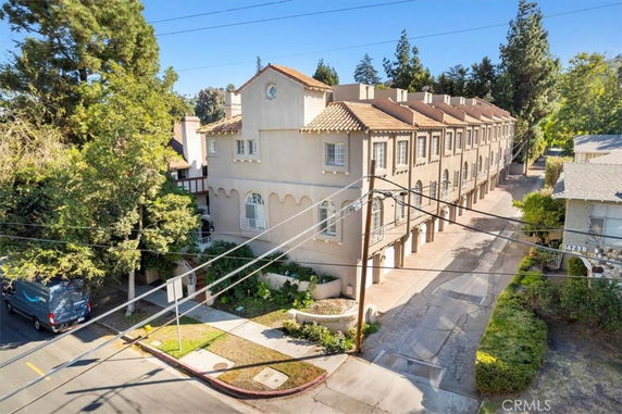 Front view of a multi-story townhouse complex with balconies and a tiled roof.