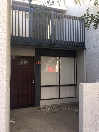 Front view of a two-story building with a balcony and a glass window beside a wooden door.
