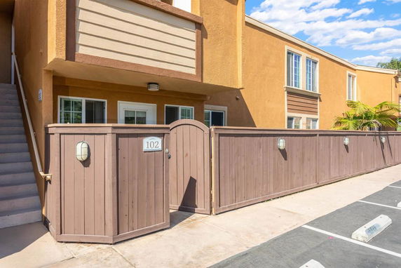 Front view of a two-story apartment building with a fenced entrance.