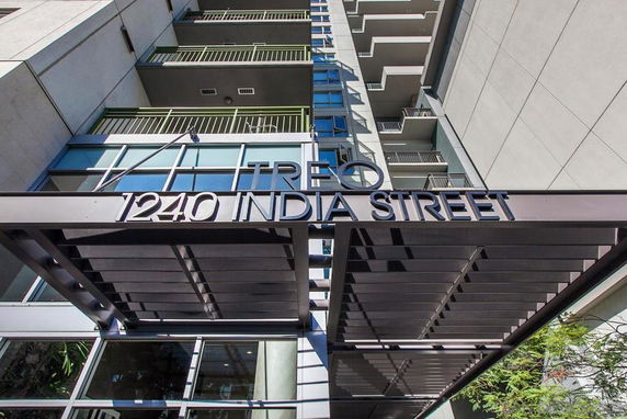 Front view of a multi-story building with balconies and an address sign.