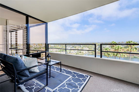 Balcony with seating area offering a panoramic view of surrounding landscape and water.