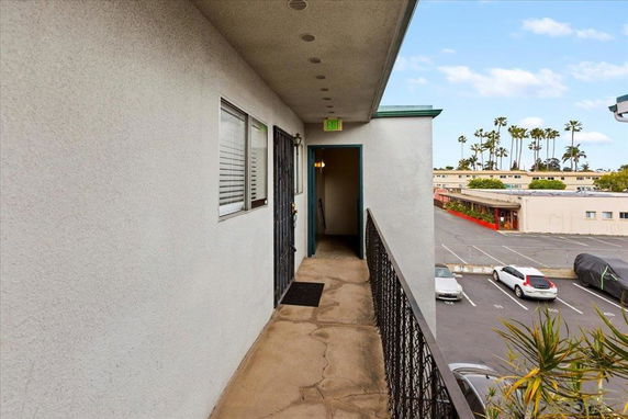 Exterior walkway of a building overlooking parking area with several parked cars.